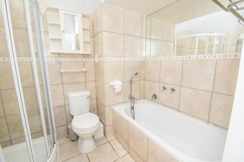 a bathroom with a toilet and a bath tub at Goose Valley Golf Estate Unit J6 in Plettenberg Bay
