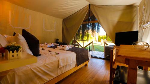 Green Pine Bungalows & Beach Luxury Concept في أولدينيس: غرفة نوم بسرير وتلفزيون وبيانو