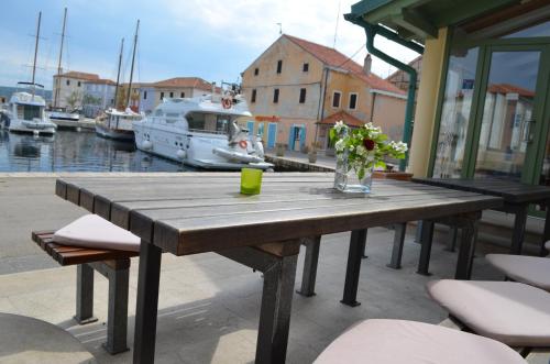 a wooden table with a vase of flowers on it at Hotel Televrin in Nerezine