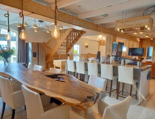 a dining room with a large wooden table and white chairs at Pura Vida Panorama in Oud-Ade