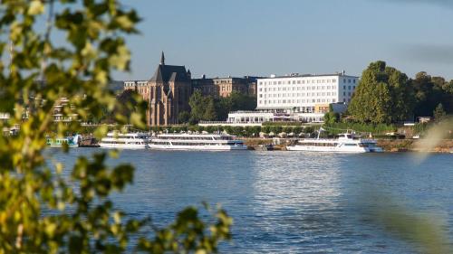 two boats are docked on a river in a city at AMERON Bonn Hotel Königshof in Bonn