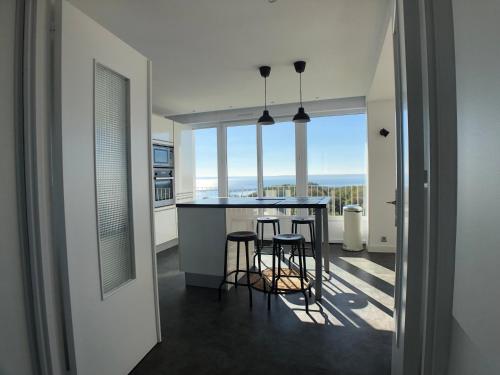 une cuisine avec un bar avec tabourets et vue dans l'établissement Superbe appartement avec une vue mer panoramique, à Brest