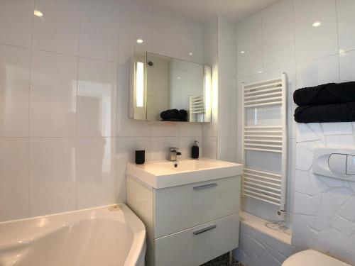 une salle de bain blanche avec un lavabo et une baignoire dans l'établissement Superbe appartement avec une vue mer panoramique, à Brest