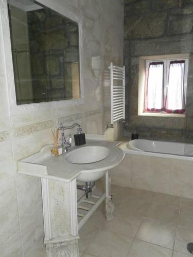 a white bathroom with a sink and a tub and a sink at Montanhas do Douro in Paredes da Beira
