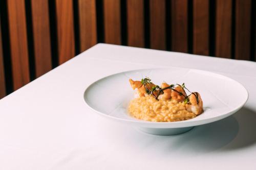 a white bowl of rice with shrimp on a table at Montebelo Vista Alegre Ílhavo Hotel in Ílhavo