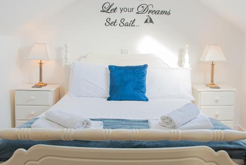 białe łóżko z niebieską poduszką i ręcznikami w obiekcie 1844 Seascape Cottage Is located on the Wild Atlantic Way w mieście Fanore