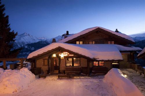 a log cabin in the snow at night at Hotel Ristoro Vagneur in Saint Nicolas