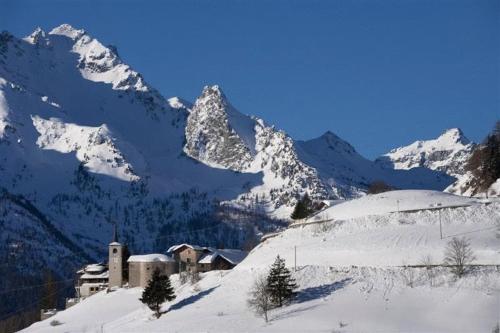 a snow covered mountain with a church in the foreground at Hotel Ristoro Vagneur in Saint Nicolas