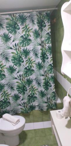 a bathroom with a toilet and a green and white wallpaper at Home sweet home in Costa de Antigua