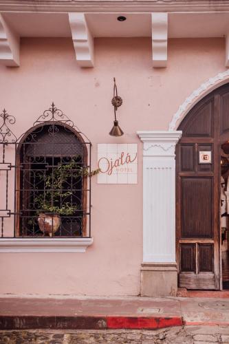 a pink building with a window with a potted plant at Ojala in Antigua Guatemala