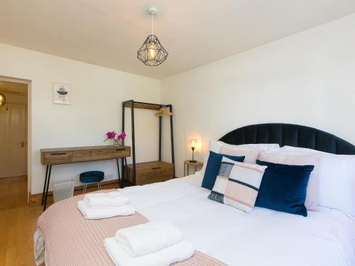 een slaapkamer met een groot wit bed met blauwe kussens bij Trengoff in St Ives