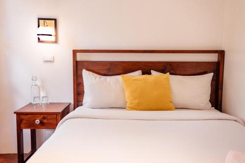 a bed with a wooden headboard and a yellow pillow at Ojala in Antigua Guatemala