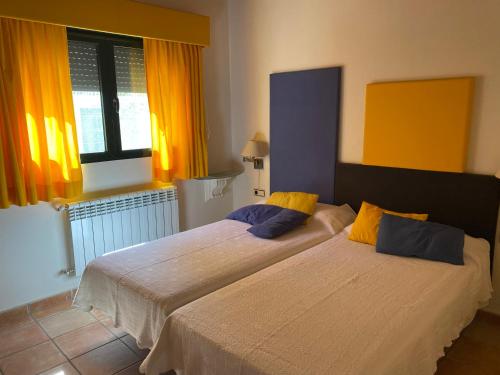 2 camas en un dormitorio con cortinas de color naranja y amarillo en Casa Rural 3 en un fantástico legado en Alfacar