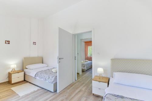 a white bedroom with two beds and a mirror at Cascada villas by Adex Travel in Starigrad-Paklenica