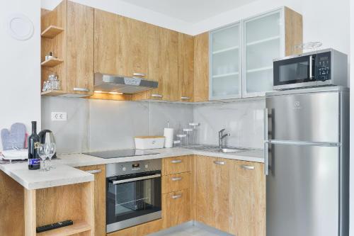 a kitchen with wooden cabinets and a stainless steel refrigerator at Cascada villas by Adex Travel in Starigrad-Paklenica