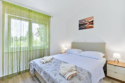 a bedroom with a bed with white sheets and a window at Cascada villas by Adex Travel in Starigrad-Paklenica
