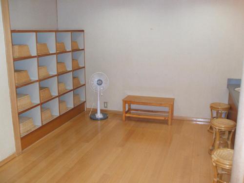 a room with a fan and a table and shelves at Annex Fujiya Ryokan in Kaminoyama