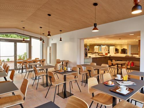 un restaurant avec des tables et des chaises et une cuisine dans l'établissement Hôtel REVOTEL Nancy Centre Gare et Congrès, à Nancy