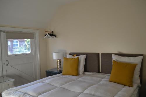 1 dormitorio con 1 cama con 2 almohadas amarillas en Frinton Escapes - The Cottage, en Frinton-on-Sea