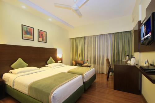 a hotel room with a large bed and a television at La Sara Hometel in Bangalore