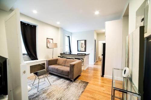 a living room with a couch and a desk at NEWLY RENOVATED HEART OF LOWER EAST SIDE 2BR 1BA, 5 MIN WALK TO SOHO, 1 BLOCK TO WHOLE FOODS, WASHER DRYER! in New York