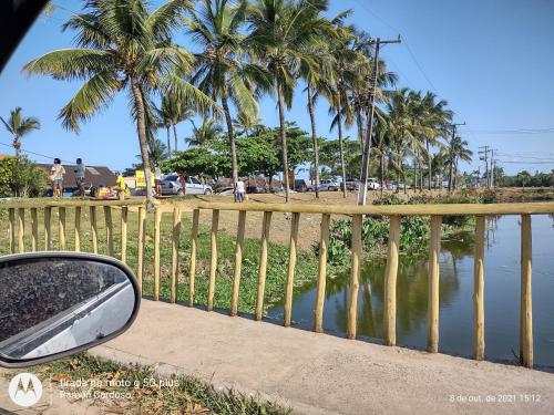 a side view mirror of a car next to a fence with palm trees at AP Praia - Vog 2 quartos com AR e D'Ouro Park-Rua dos Tangarás, 20 todo climatizado in Ilhéus