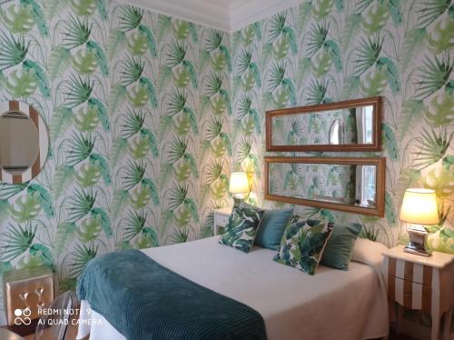 a bedroom with a bed and a wall covered in wallpaper at Alojamiento Buciero in Santoña