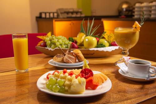 a wooden table with two plates of fruit and drinks at Hotel La Venta Inn Villahermosa in Villahermosa