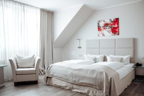 a white bedroom with a large bed and a chair at Clostermanns Hof in Niederkassel