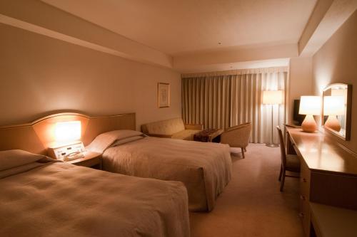 a hotel room with two beds and a desk at Bellino Hotel Ichinoseki in Ichinoseki