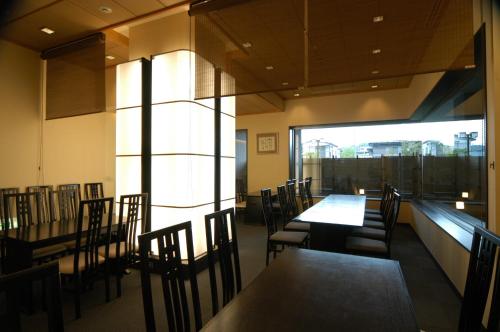 a dining room with tables and chairs and a large window at Bellino Hotel Ichinoseki in Ichinoseki