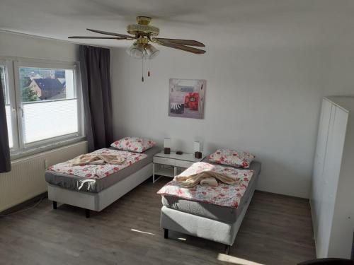 Cette chambre comprend deux lits et un ventilateur de plafond. dans l'établissement Apartment 31K, à Castrop-Rauxel