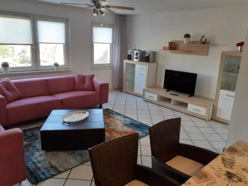 sala de estar con sofá rosa y TV en Apartment 31K en Castrop-Rauxel