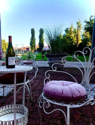 a table and chairs with a bottle of wine and a pillow at Hotel Villa Montanarini in Villarotta