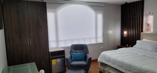 a bedroom with a bed and a chair and a desk at Hosteria Santa Ana in Azogues