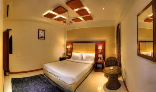 a bedroom with a bed and a chair in it at Rajmahal Inn in Mysore