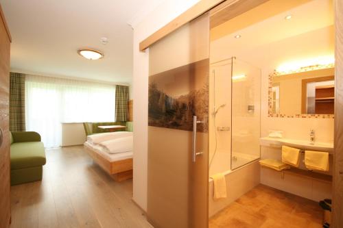 a bathroom with a shower and a bedroom with a bed at Alpenhotel Neuwirt in Schladming