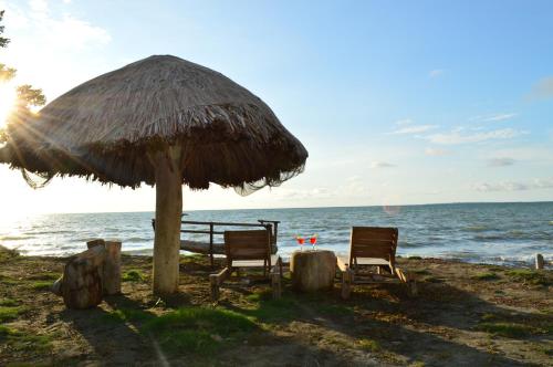 two chairs under a straw umbrella on the beach at Palmar del viento cabaña frente al mar in Moñitos