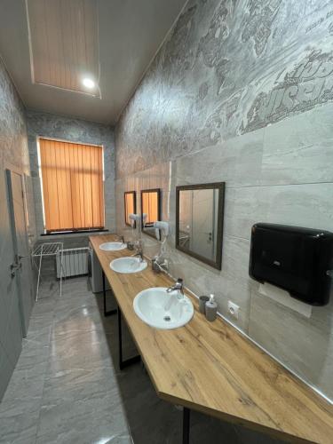 a bathroom with three sinks and a tv on the wall at Хостел Baltson in Vladikavkaz