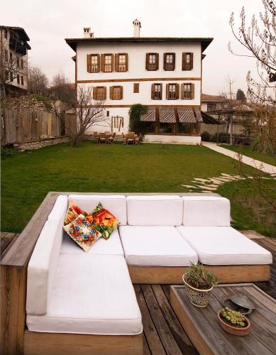 a white couch on a deck with a house in the background at Gulevi Safranbolu in Safranbolu