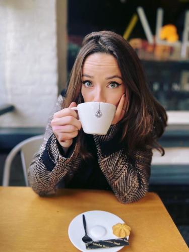 a woman sitting at a table drinking a cup of coffee at Alex Maastricht in Maastricht