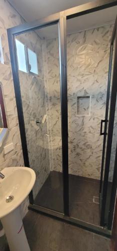 a shower with a glass door next to a sink at Hosteria Santa Ana in Azogues