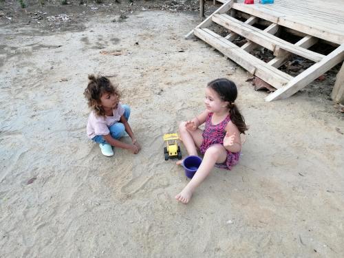 two little girls playing with a toy truck in the sand at Palmar del viento cabaña frente al mar in Moñitos