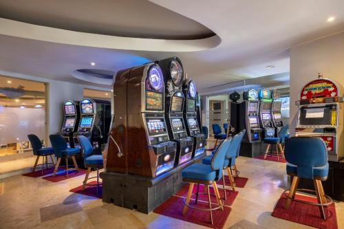 un casino con varias máquinas tragaperras y sillas azules en Iberostar Grand Rose Hall en Montego Bay