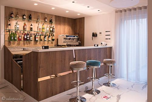a bar with two stools and bottles of wine at Hotel San Vincenzo Resort in Policoro