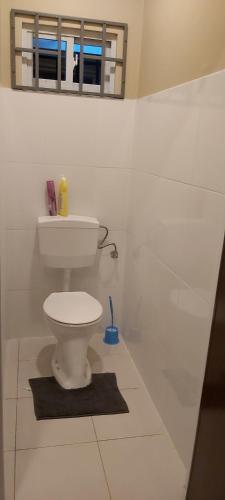 a white bathroom with a toilet and a mirror at Waterland Suites in Paramaribo