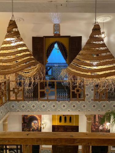 two large chandeliers in a room with a fireplace at RIAD Dar Ouezzani in Rabat