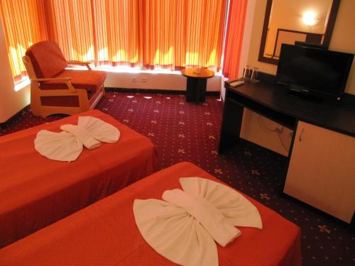 ein Hotelzimmer mit zwei Betten, einem Stuhl und einem Fernseher in der Unterkunft Maverick Hotel in Sonnenstrand