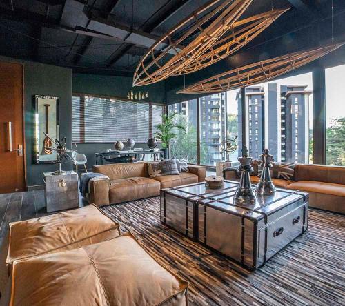 a living room with leather furniture and a large room with windows at Parque Pinares Pucón Chile in Pucón