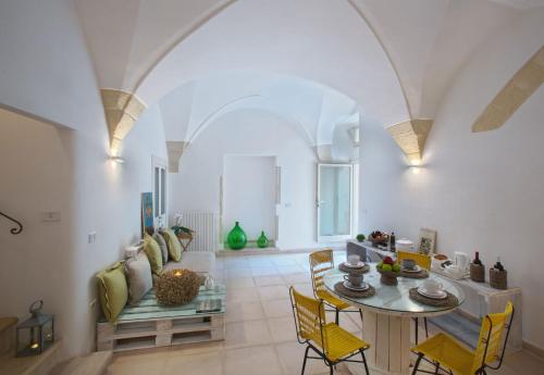 a living room with a table and yellow chairs at Corte dei Romiti Apartment in Lecce